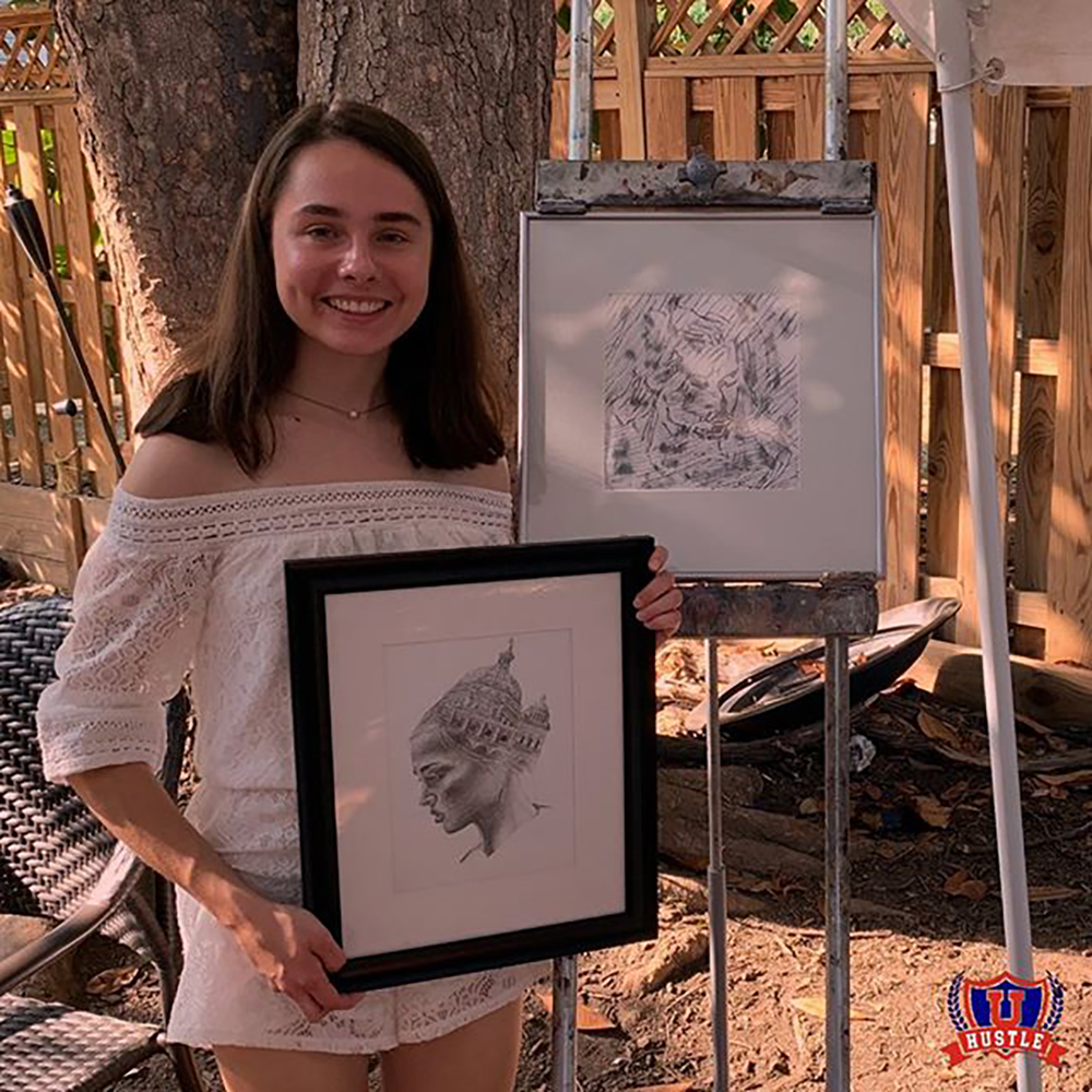 @UNIVERSITYHUSTLE/INSTAGRAM | Natalia Suska (COL ’22) stands in front of her booth showcasing her artwork at UHustle’s first ever Hustle fair, an event dedicated to connecting student entrepreneurs with a broader Georgetown audience.