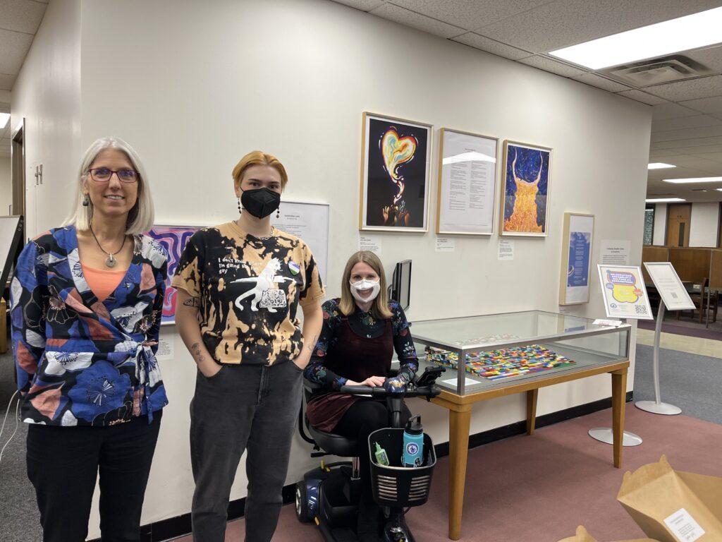 Beth Marhanka, Lauinger Library's head of outreach and engagement, Em Aufuldish of the art and art history department and Amy Kenny, director of the Disability Cultural Center, stand in front of the ACDC exhibit during its Oct. 11 opening reception.