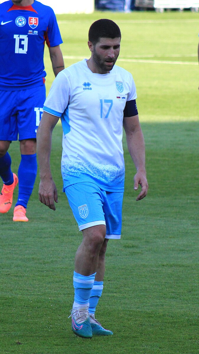 San Marino midfielder Alessandro Golinucci joining a team huddle during a match timeout.